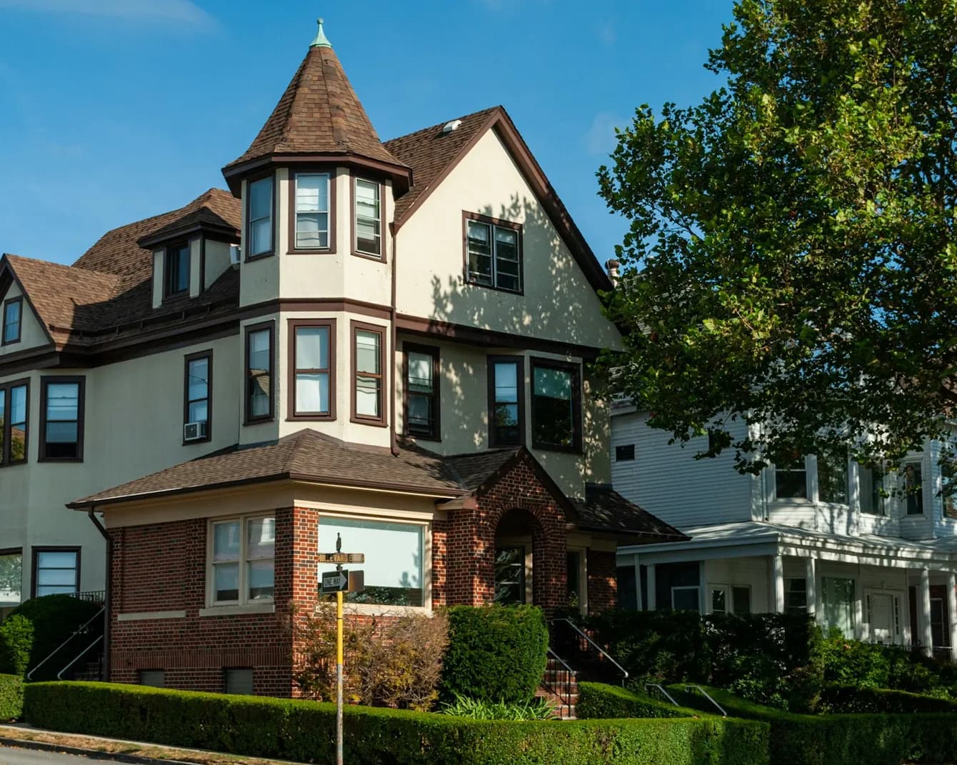 A classic home with manicured hedges on a sunny street
